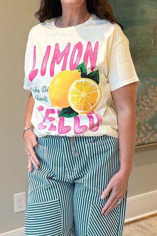 Woman wearing a colorful t-shirt with lemons and text, standing in an indoor setting.