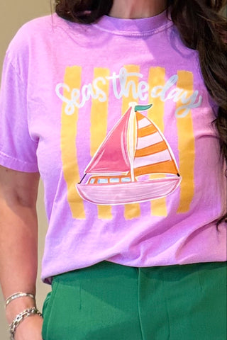 Person wearing a pink t-shirt with a sailboat graphic and 'Sail the day' text.